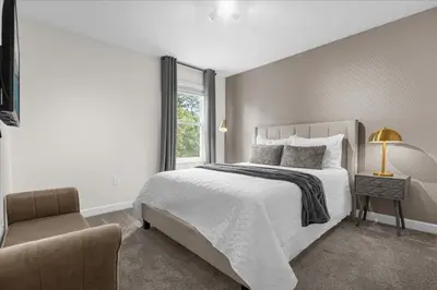 a white bedroom with a bed and a chair at 7 Bedroom 6 Bathrooms Storey Lake Resort home in Kissimmee
