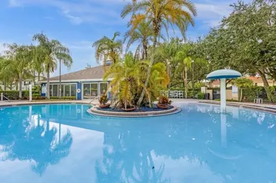 a large pool with palm trees and a building at 3 Bedrooms 2 Bathrooms Lucaya Village townhouse in Kissimmee