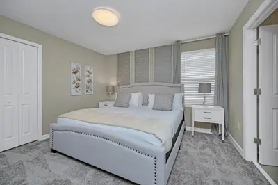 a white bedroom with a large bed and a table at 9 bedrooms 5 Bathrooms Storey Lake Game Room Too home in Kissimmee