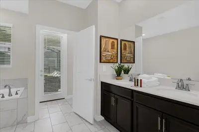 a white bathroom with two sinks and a shower at 8 Bedroom & Theme Rooms For Kids In Storey Lake home in Kissimmee