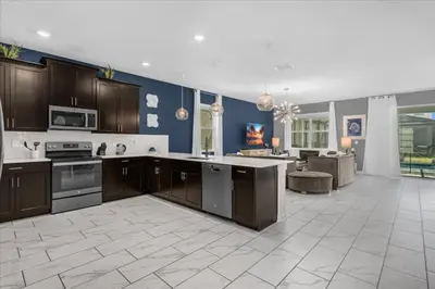 a large kitchen with brown cabinets and a blue wall at 8 Bedroom & Theme Rooms For Kids In Storey Lake home in Kissimmee