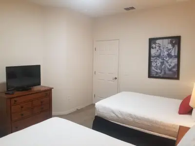 a bedroom with two beds and a tv and a dresser at 3 Bed 2 Bath Condo in Lucaya Village Near Disney townhouse in Kissimmee