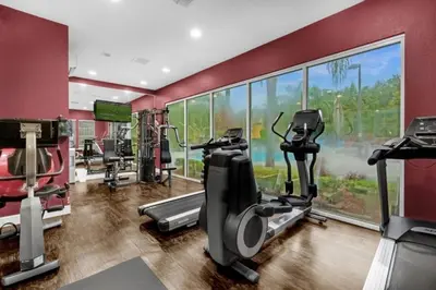 a gym with several tread machines and a large window at 3 Bed 2 Bath Condo in Lucaya Village Near Disney townhouse in Kissimmee