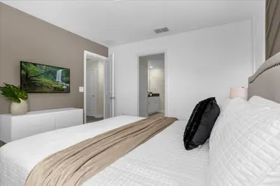 a white bedroom with a large bed and a tv at 9 bed Home Storey Lake home in Kissimmee