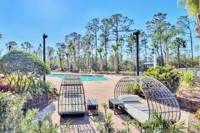 a patio with two chairs and a pool at Modern 3BR Condo w Private Patio 7min to Disney in Orlando