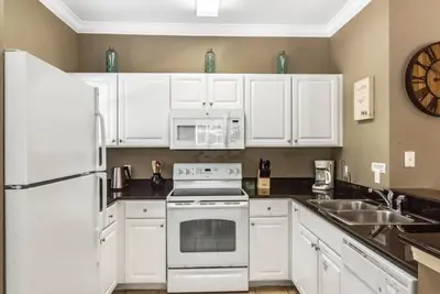 a kitchen with white appliances and a clock on the wall at 4 Bedrooms 3 Bathrooms Lucaya Village townhouse in Kissimmee