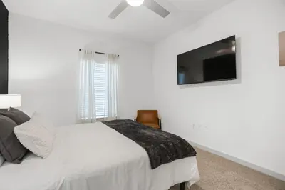 a white bedroom with a bed and a flat screen tv at Magical Retreat Outside of Disney in Orlando