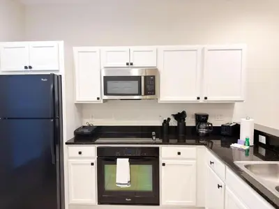 a kitchen with white cabinets and a black microwave at ER3047WOR - Cozy 3BD Townhome w/ Private Hot Tub in Kissimmee