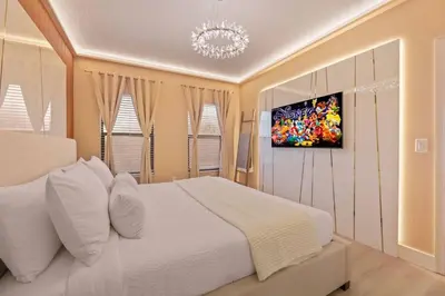 a bedroom with a white bed and a tv on the wall at Casa 5Q Moderna c/ Piscina – 15min Disney in Orlando