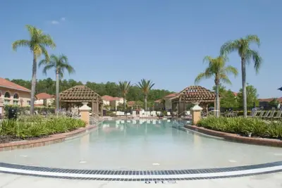 a swimming pool at a resort with palm trees at Modern Pool Townhome Minutes to Disney in Kissimmee