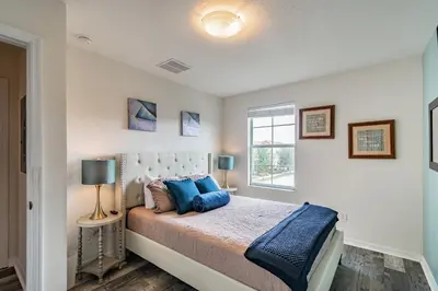 a bedroom with a bed with blue pillows and a window at Modern Pool Townhome Minutes to Disney in Kissimmee