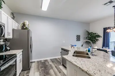 a kitchen with a sink and a refrigerator at Modern Pool Townhome Minutes to Disney in Kissimmee