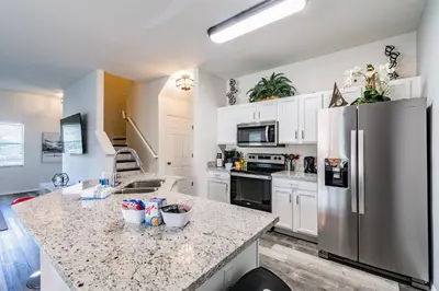 a kitchen with a stainless steel refrigerator and white cabinets at Modern Pool Townhome Minutes to Disney in Kissimmee
