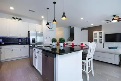 a kitchen with white cabinets and a kitchen island with chairs at Casa c/ 9Q, piscina, spa e cinema! Perto da Disney in Kissimmee