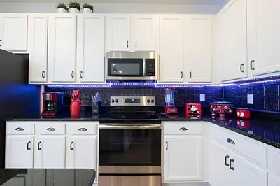 a kitchen with white cabinets and a microwave at Casa c/ 9Q, piscina, spa e cinema! Perto da Disney in Kissimmee
