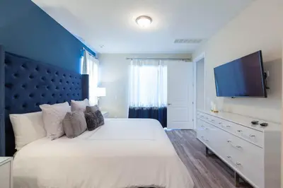 a bedroom with a large white bed and a flat screen tv at Incredible 8BR PetFriendly Encore Resort next to Disney - 7474 in Orlando
