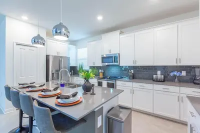 a kitchen with white cabinets and a table with chairs at Gorgeous 5BR at Storey Lake next to Disney - 2924 in Kissimmee