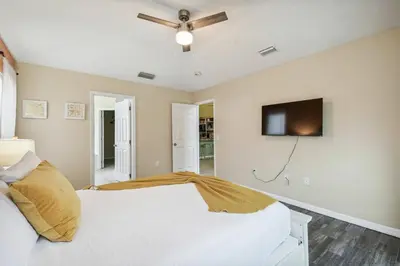a bedroom with a white bed and a flat screen tv at Lake Berkley 5Q, Piscina Aquecida, Perto Disney in Kissimmee