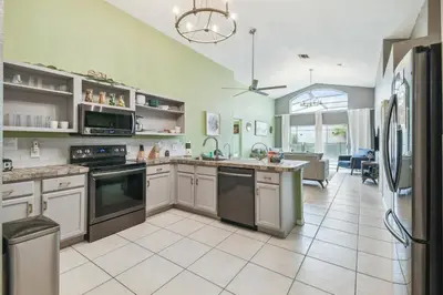 a kitchen with stainless steel appliances and a living room at Lake Berkley 5Q, Piscina Aquecida, Perto Disney in Kissimmee