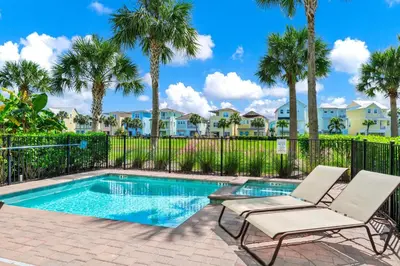a villa with a swimming pool with two chairs and palm trees at The Lime Life Cottage Near Disney With Margaritaville Resort And Island H20 Waterpark Access - 8056Sh in Orlando