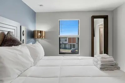 a white bedroom with a white bed and a window at The Hub Beautiful Townhome Near Parks in Kissimmee