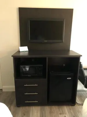 a black entertainment center with a tv and a microwave at Green Palms Extended Stay in Kissimmee