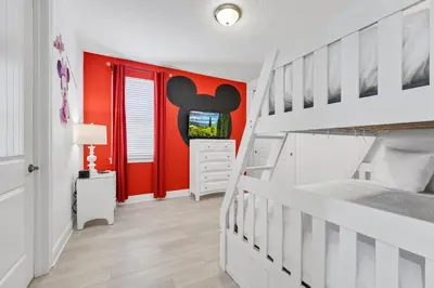 a bedroom with a bunk bed and a red wall at Home With Movie Theater, Game & Theme Room Near Disney With Resort & Waterpark Access - 7621Wi in Orlando