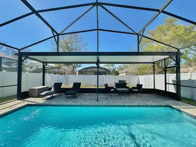 a swimming pool with a pavilion with chairs and a table at Charming 4 Bdr Villa near Disney in Kissimmee