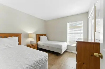 a bedroom with a bed and a chair and a window at Vila 4Q com Piscina Privativa – Lake Berkley in Kissimmee