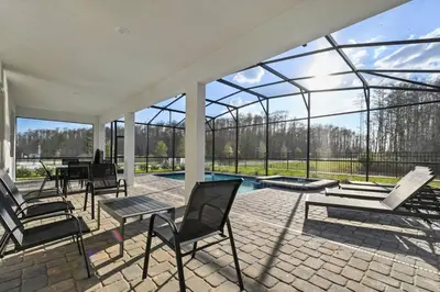 a conservatory with chairs and a table and a pool at Casa 9Q em Resort c/ Piscina – 11km da Disney in Kissimmee