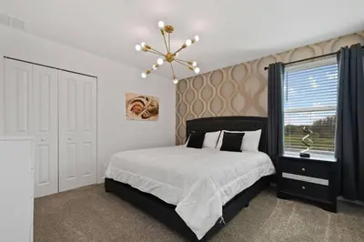 a bedroom with a bed and a window and a chandelier at Casa 9Q em Resort c/ Piscina – 11km da Disney in Kissimmee