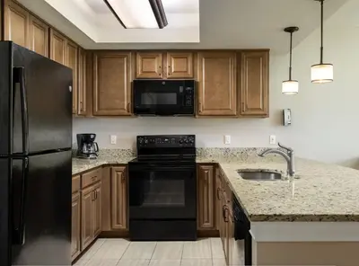 a kitchen with wooden cabinets and a black refrigerator at Weekly rental at Orange Lake Resort for a family of 8 people in Orlando