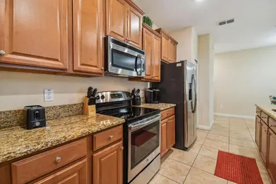a kitchen with wooden cabinets and a stove and refrigerator at 4Q/ Paradise Palms com Piscina Privativa in Kissimmee
