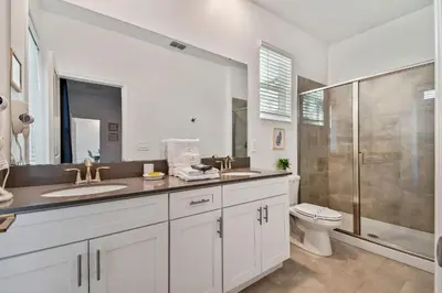 a bathroom with two sinks and a shower and a toilet at Storey Lake * Linda Casa 5 quartos com sala de jogos in Kissimmee