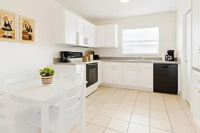 a white kitchen with white cabinets and black appliances at Casa 3 Quartos c/ Piscina perto da Disney! in Kissimmee