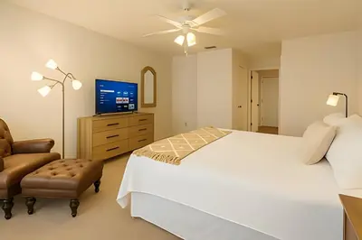 a bedroom with a bed and a tv and a chair at Casa 3 Quartos c/ Piscina perto da Disney! in Kissimmee