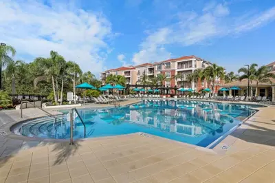 a swimming pool at a resort with chairs and umbrellas at Casa 3Q no Vista Cay- Perto da Universal in Orlando
