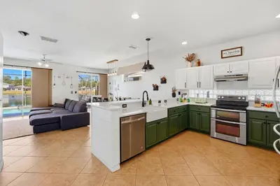a kitchen with green cabinets and a living room at 2989 - Flamingo Farmhouse in Kissimmee