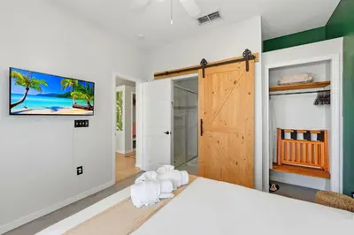 a bedroom with a white bed and a wooden door at 2989 - Flamingo Farmhouse in Kissimmee
