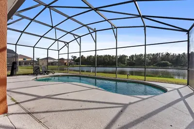 a swimming pool under a glass roof with a view of a lake at Comfortable 6-Bedroom Getaway Near Top Attractions in Kissimmee