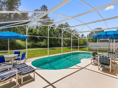 a swimming pool with chairs and umbrellas at Holiday Home Ferienvilla mit Garten- Grill und Terrasse by Interhome in Orlando