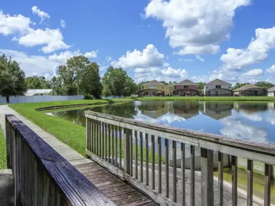 a bridge over a pond with houses in the background at Holiday Home 4-Schlafzimmer-Ferienhaus mit Whirlpool by Interhome in Kissimmee