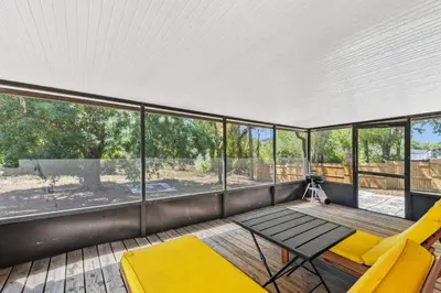a screened in porch with a table and yellow chairs at 7694 Indian Ridge Trail S in Orlando