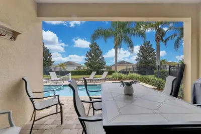 a patio with a table and chairs and a pool at Unforgettable 8-Bedroom Luxury Retreat in Orlando