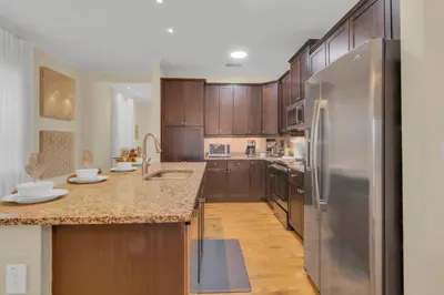 a kitchen with wooden cabinets and a stainless steel refrigerator at Unforgettable 8-Bedroom Luxury Retreat in Orlando