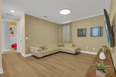 a living room with a couch and a tv at Unforgettable 8-Bedroom Luxury Retreat in Orlando