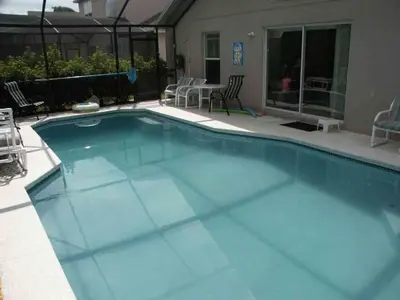 a swimming pool with blue water in a yard at Lake Berkley 5 bedroom 3 bath villa near Disneyland in Kissimmee