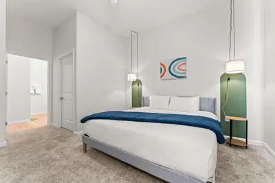 a bedroom with a large white bed with blue blanket at Riviere 3BR Apartment Stylish King Family Pets Friendly Pool & Gym Near Epic Universe in Orlando