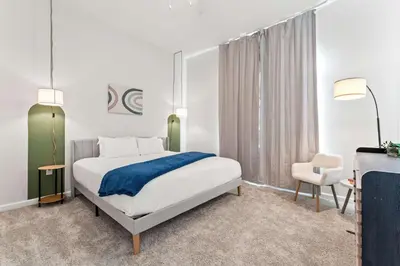 a white bedroom with a bed and a chair at Riviere 3BR Apartment Stylish King Family Pets Friendly Pool & Gym Near Epic Universe in Orlando