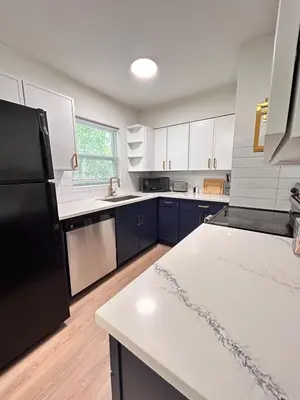 a kitchen with white cabinets and a black refrigerator at Cozy Modern 3BR Escape - Sanford in Sanford